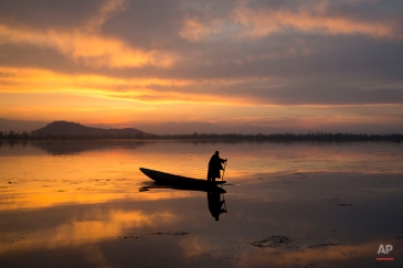 A Kashmiri fisherman rows his Shikara, or traditional boat, during sunset at the Dal Lake in Srinagar, Indian controlled Kashmir, Tuesday, March 29, 2016.Nestled in the Himalayan mountains and known for its beautiful lakes and saucer-shaped valleys, the Indian portion of Kashmir, is also one of the most militarized places on earth. (AP Photo/Dar Yasin)