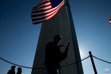 Visitors to the National Mall walk around the base of the Washington Monument in Washington. (AP Photo/Andrew Harnik)