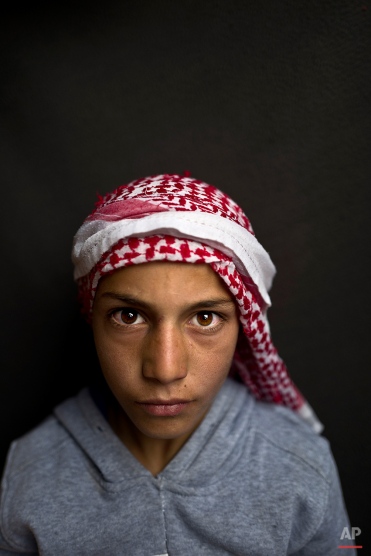 In this Sunday, March 13, 2016 photo, Syrian refugee boy Mohammed Bandar, 12, from Hama, Syria, poses for a picture at an informal tented settlement near the Syrian border on the outskirts of Mafraq, Jordan. "I want to become a doctor to be able to help people," says Bandar. (AP Photo/Muhammed Muheisen)