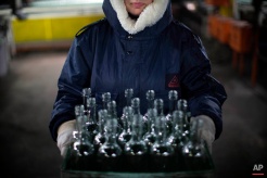 In this Wednesday, Jan. 27, 2016 photo, an employee carries a box of defective glass bottles to be recycled at the Phoenicia Glass Works Ltd. factory in the southern Israeli town of Yeruham. Factory workers grind these rejects into shards and pile them outside. Recycled glass bottles from across the country are sent here and ground up, too. The glass pieces are shoveled into the ovens to be fired into new glass bottles. Sand, the basic ingredient of glass, is hauled in from a nearby desert quarry. (AP Photo/Oded Balilty)