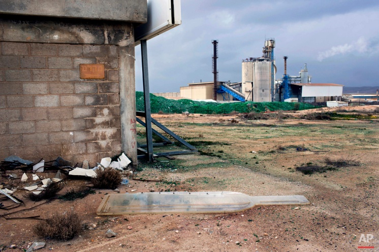 In this Tuesday, Jan. 26, 2016 photo, a broken sign lies on the ground at the Phoenicia Glass Works Ltd. factory in the southern Israeli town of Yeruham. Phoenicia Glass Works Ltd. produces a million bottles and containers a day for beverage giants Coca Cola, Pepsi, and Heineken, as well as Israeli wineries and olive oil companies. Every day, about 300,000 bottles come out of the ovens with defects. (AP Photo/Oded Balilty)