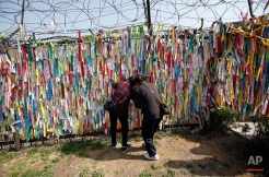 Visitors look through a wire fence decorated with ribbons with messages wishing for the reunification of the two Koreas at the Imjingak Pavilion near the border with North Korea, in Paju, in Seoul, South Korea, Friday, April 15, 2016. A North Korean launch of a missile on the birthday of its revered founder appears to have failed, South Korean and U.S. defense officials said Friday. (AP Photo/Lee Jin-man)