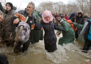 A woman cries as she crosses the river along with other migrants, north of Idomeni, Greece, attempting to reach Macedonia on a route that would bypass the border fence, Monday, March 14, 2016. (AP Photo/Vadim Ghirda)