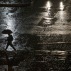 In this April 16, 2016 photo, a man walks under the rain in Santiago, Chile. Authorities say the Rio Mapocho flooded several districts of the city and landslides killed at least one person. (AP Photo/Esteban Felix)