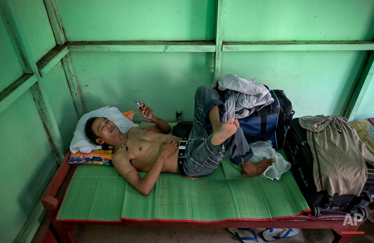 In this May 15, 2015, photo, Myint Naing, a former slave fisherman who spent more than two decades in Indonesia after being enslaved on Thai fishing boats, rests at a government hostel in Yangon, Myanmar after returning to his home country the day before. Myint, 40, is among hundreds of former slave fishermen who returned to Myanmar following an Associated Press investigation into the use of forced labor in Southeast Asia’s seafood industry. (AP Photo/Gemunu Amarasinghe)