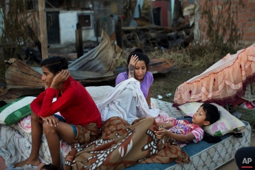 In this April 19, 2016 photo, a family wakes up after sleeping outside their collapsed home which was destroyed by an earthquake in Manta, Ecuador. The strongest earthquake to hit Ecuador in decades flattened buildings and buckled highways along its Pacific coast, sending the Andean nation into a state of emergency. (AP Photo/Rodrigo Abd)