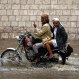 A man looks at his mobile phone while riding a motorcycle in floodwaters on a rainy day in Sanaa, Yemen, Wednesday, April 13, 2016. (AP Photo/Hani Mohammed)