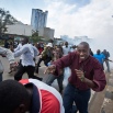 Opposition supporters, some carrying rocks, flee from clouds of tear gas fired by riot police, during a protest in downtown Nairobi, Kenya, Monday, May 16, 2016. Kenyan police have tear-gassed and beaten opposition supporters during a protest demanding the disbandment of the electoral authority over alleged bias and corruption. (AP Photo/Ben Curtis)