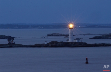 In this Aug. 25, 2016 photo, Boston Light, America's oldest lighthouse, flashes in Boston Harbor as seen from Hull, Mass. (AP Photo/Elise Amendola)